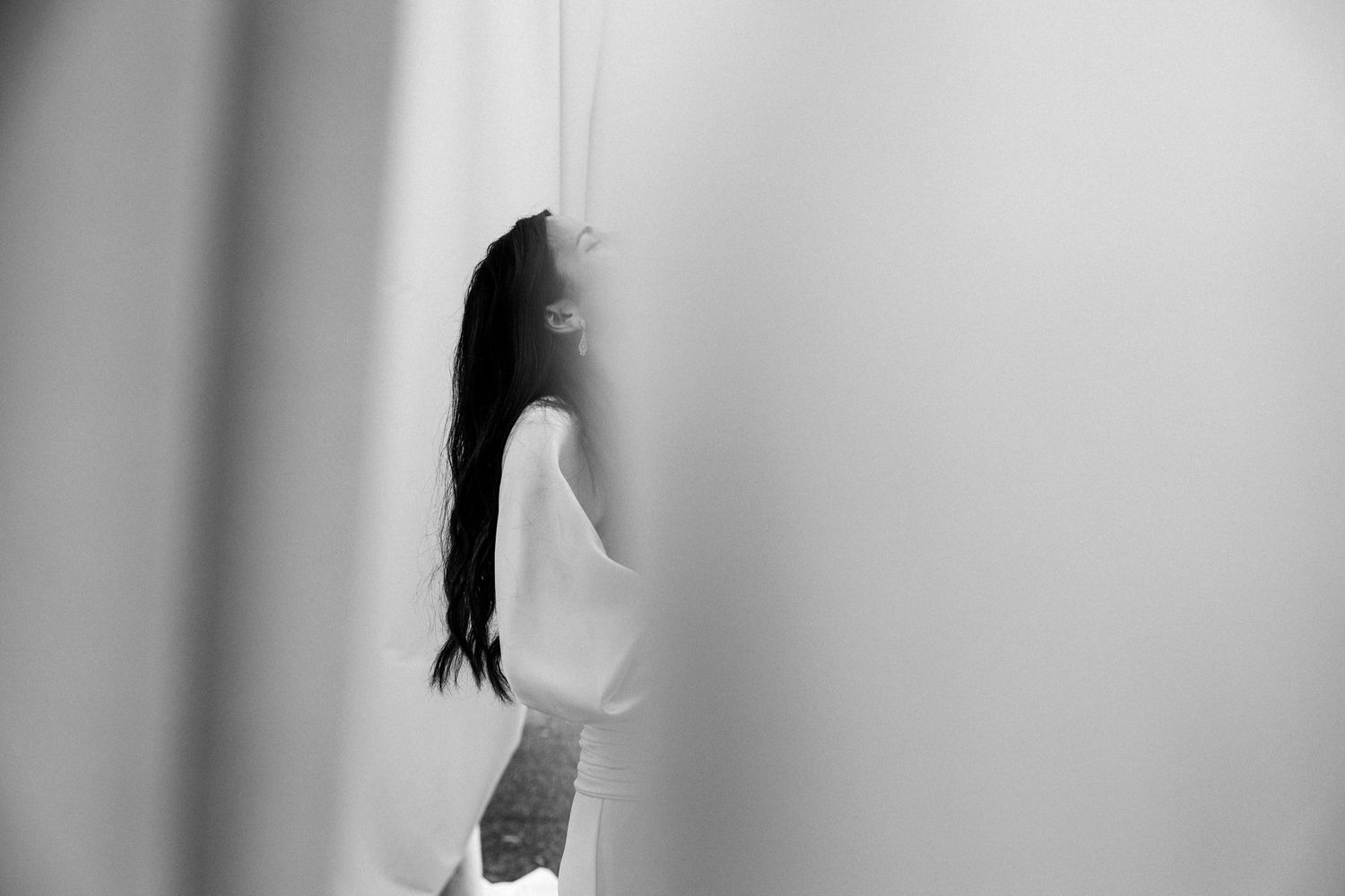 Minimalist sequence showing movement behind sheer white fabric in a studio setting.