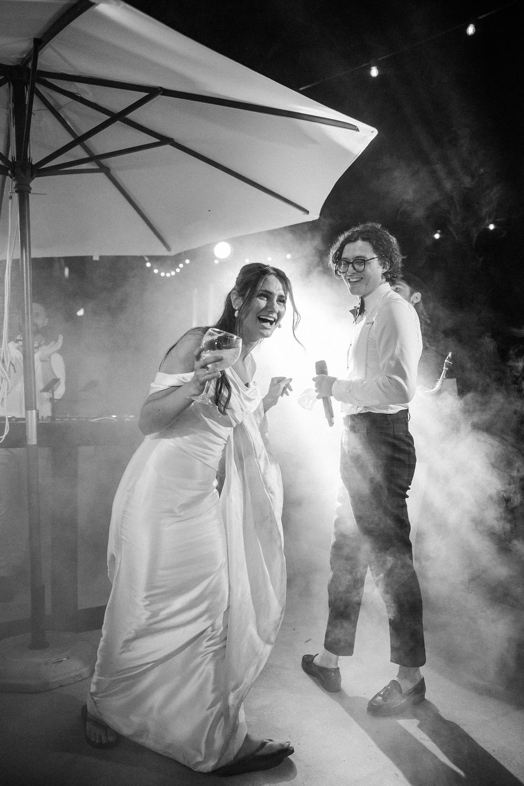 Atmospheric dance floor scene with fog machines and white umbrellas at night.