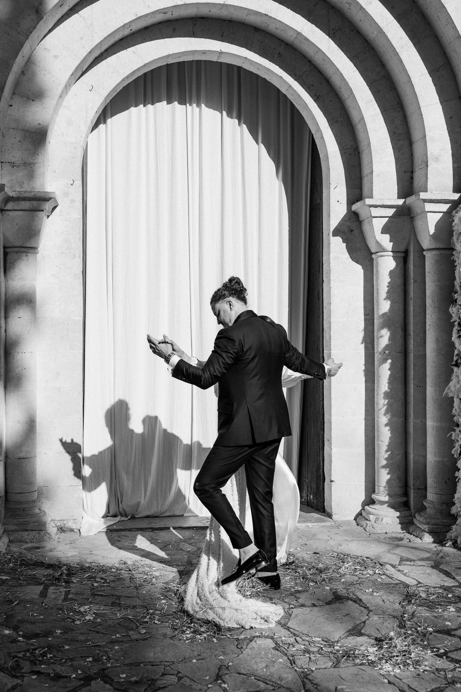 Dynamic wedding photoshoot showing dramatic movements against stone archways and white curtains.