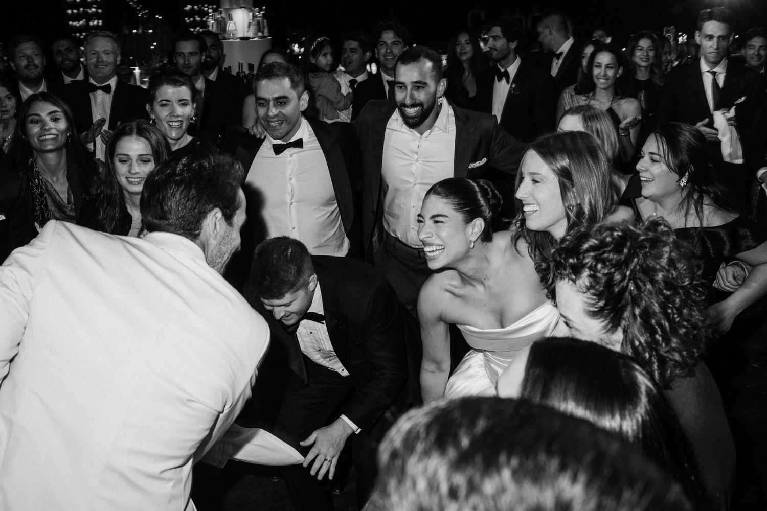 Wedding guests dance and celebrate together on a crowded dance floor at an elegant reception party.