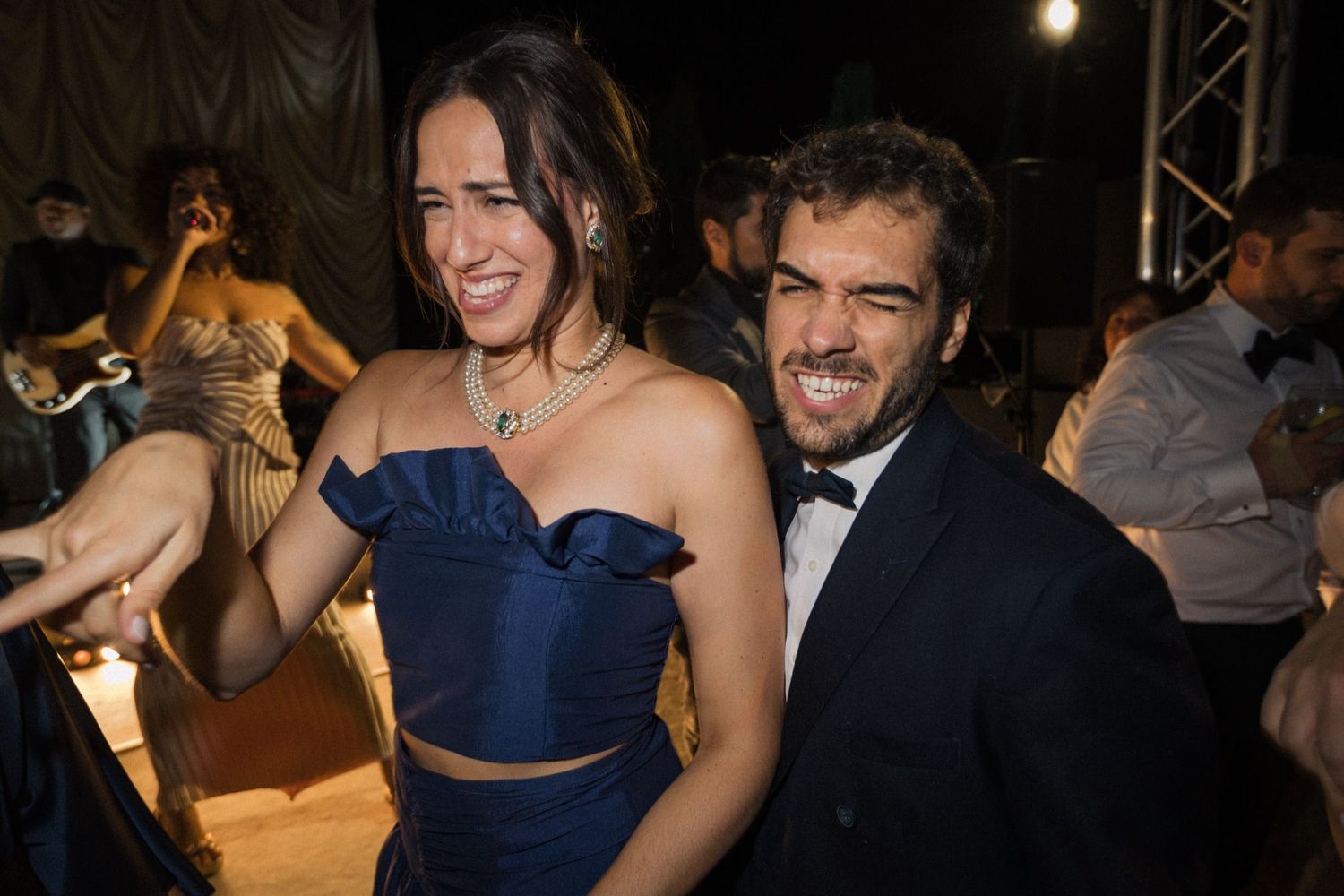 People dancing and celebrating at a dimly lit wedding reception or party venue.