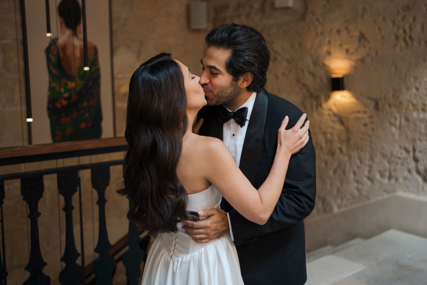 A romantic wedding couple shares an intimate moment in a rustic stone-walled venue during their first dance.