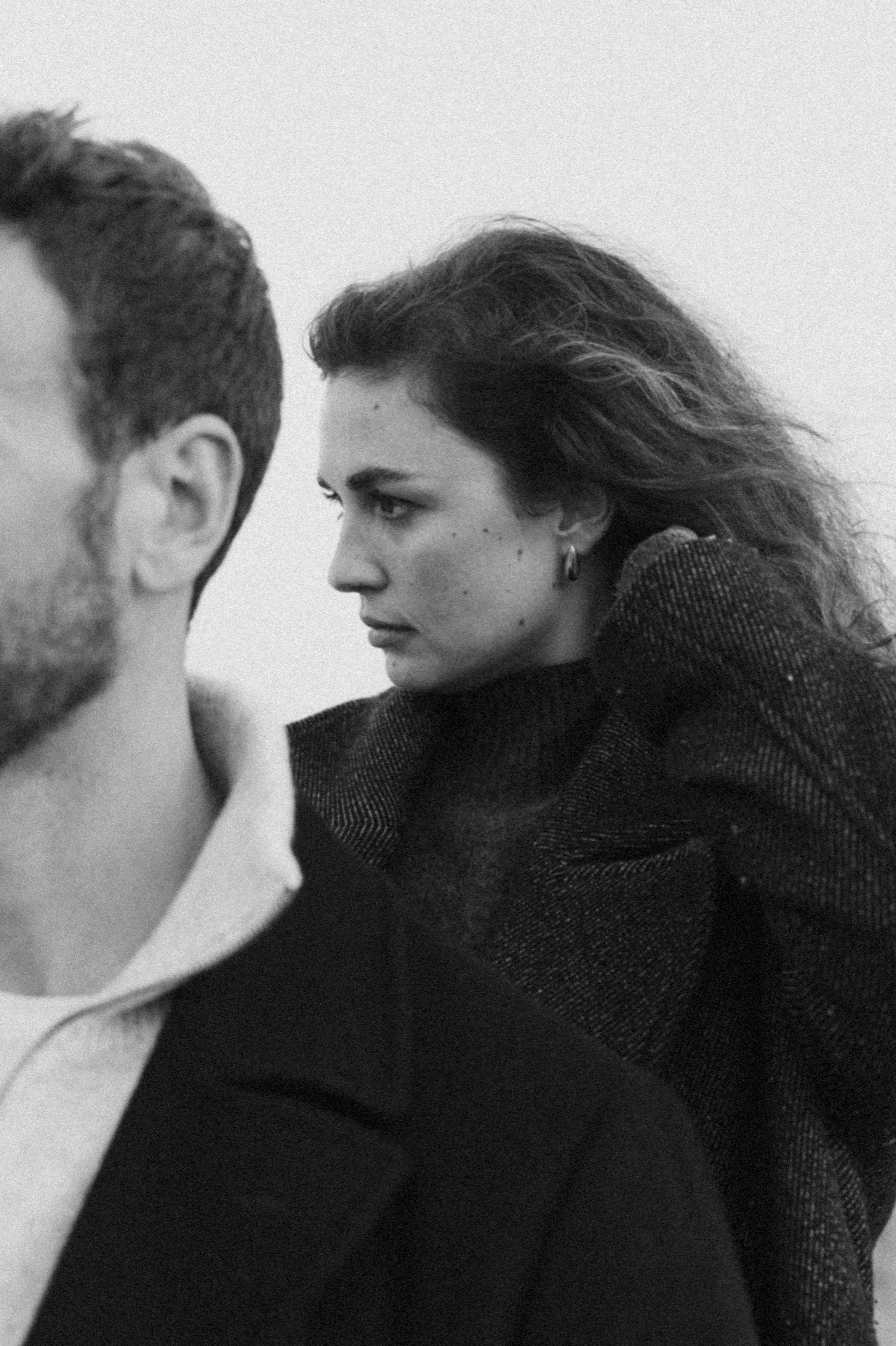 Black and white portrait of a couple in profile sharing an intimate moment against a light background.
