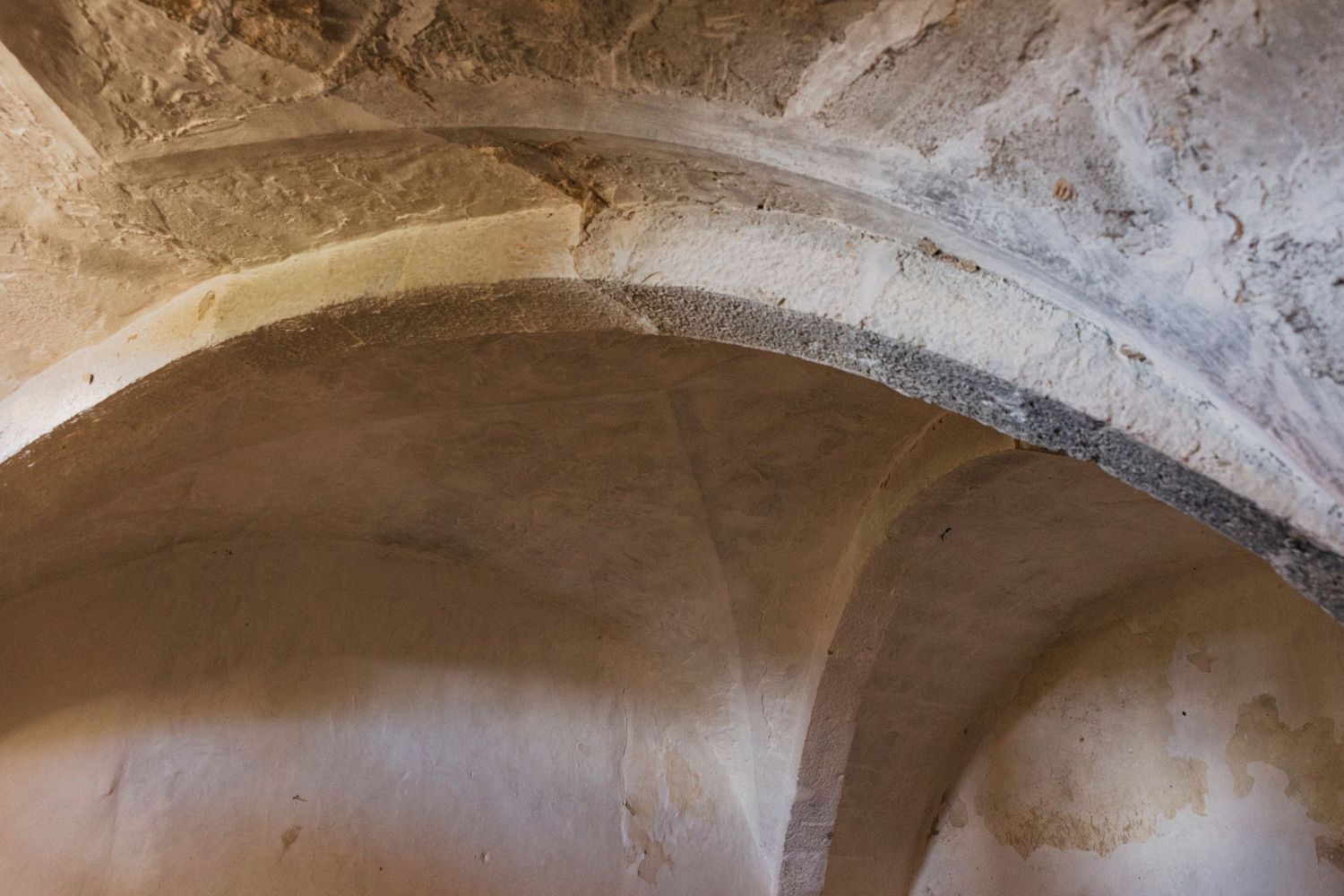 Stone archways and vaulted ceilings form a historic passageway in an ancient building.