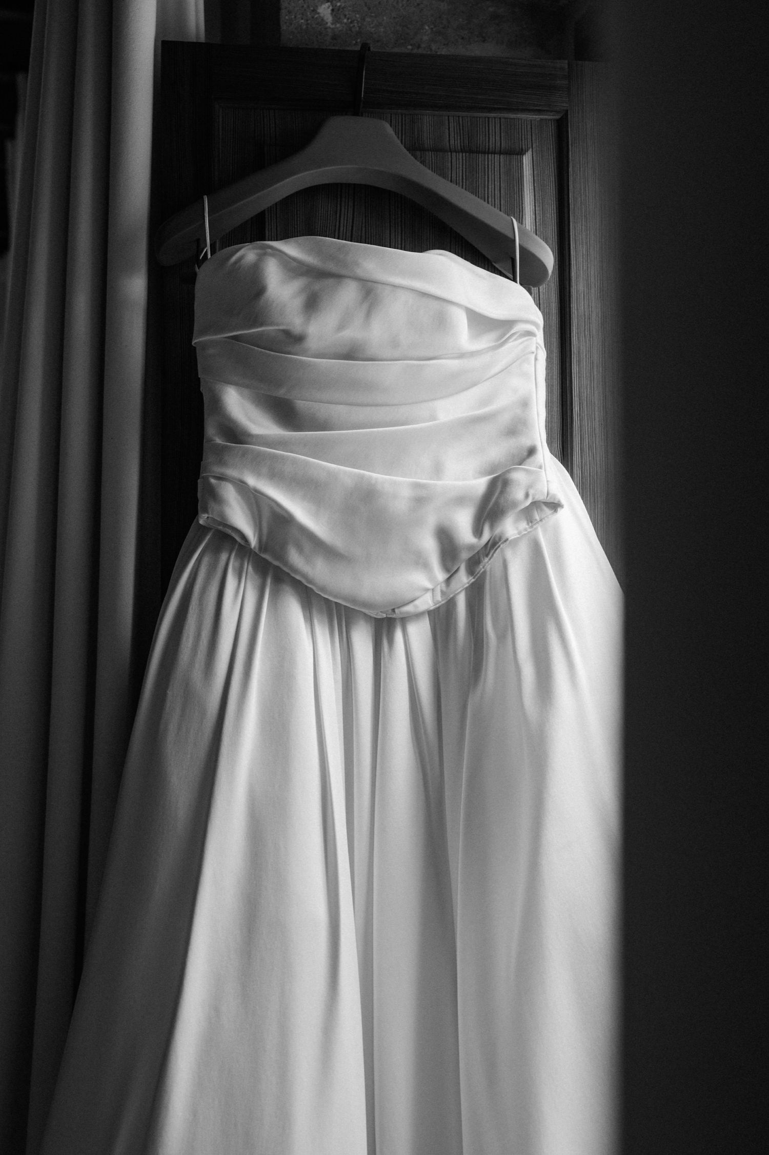 Multiple white wedding dresses hanging on display with elegant draped bodices and flowing skirts.