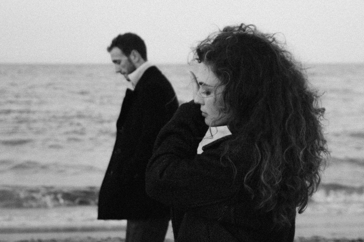Romantic black and white beach scene with silhouettes against an ocean backdrop.