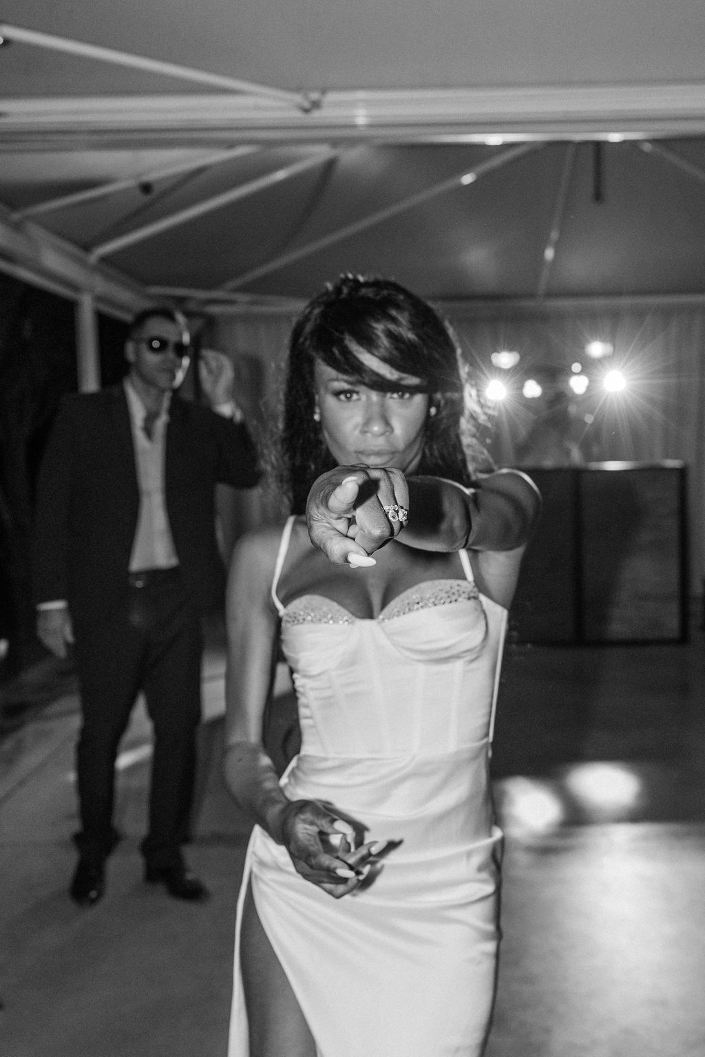 A performer in white dances in a dimly lit venue with dramatic spotlighting.