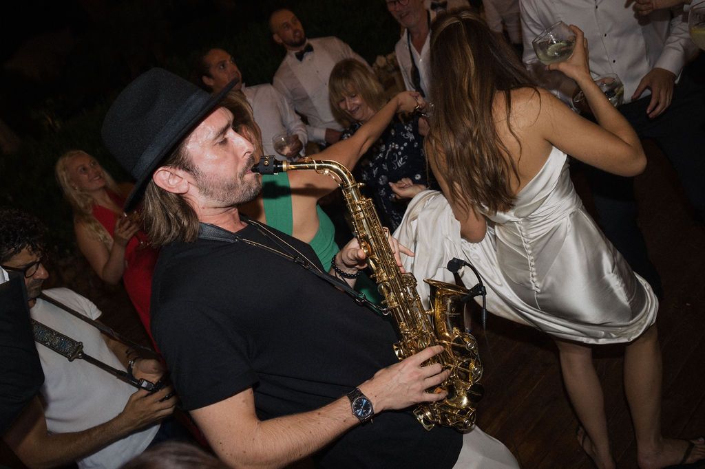 Party guests dance and celebrate with enthusiasm at a nighttime wedding reception.