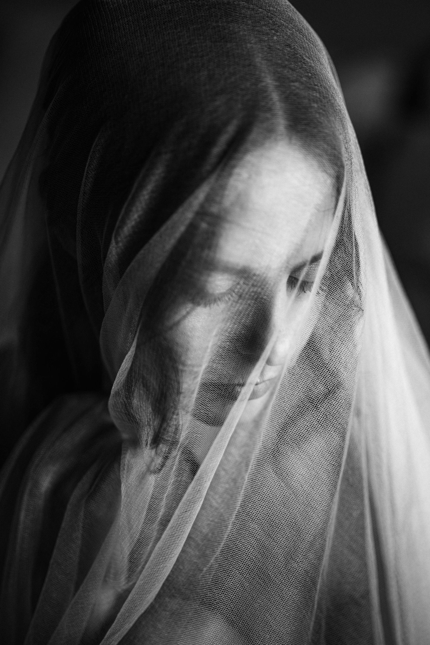 A ghostly figure shrouded in white fabric creates an ethereal and haunting artistic portrait in black and white.