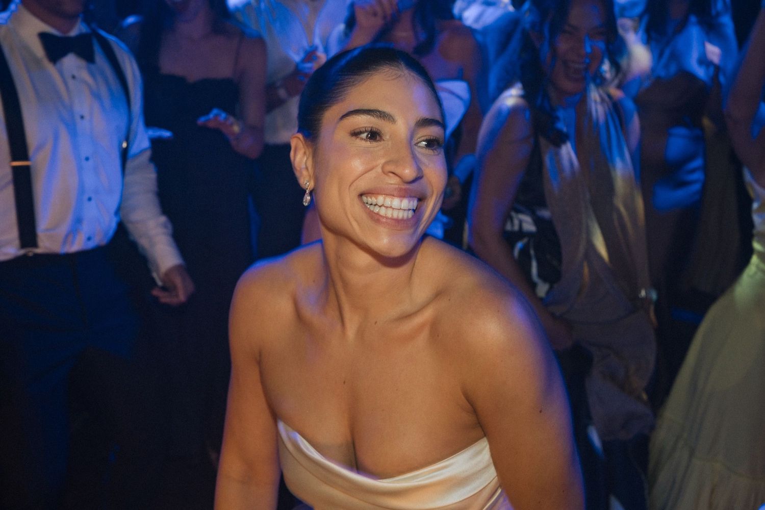 A group of people enjoying themselves at a lively party or celebration with blue lighting in the background.
