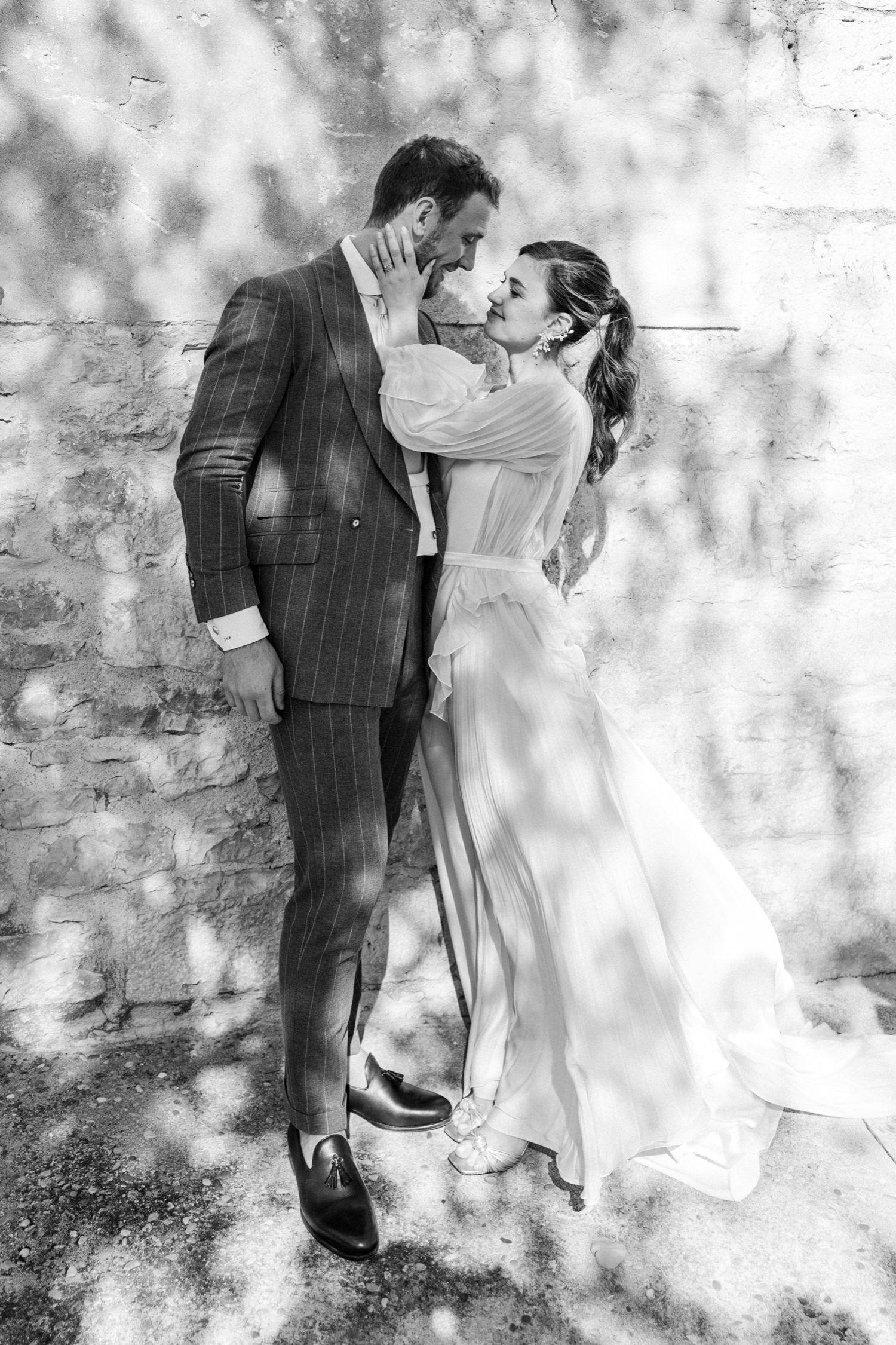 A romantic black and white photo sequence showing a couple in wedding attire embracing against a textured wall.