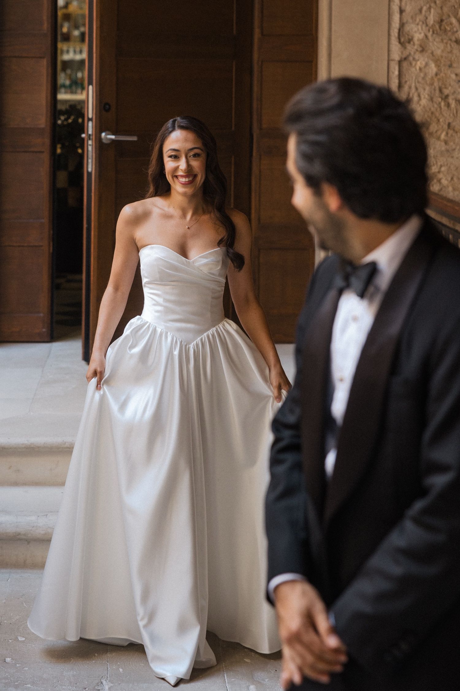 A couple shares a joyful moment during their wedding, with the bride wearing a stunning white strapless gown.