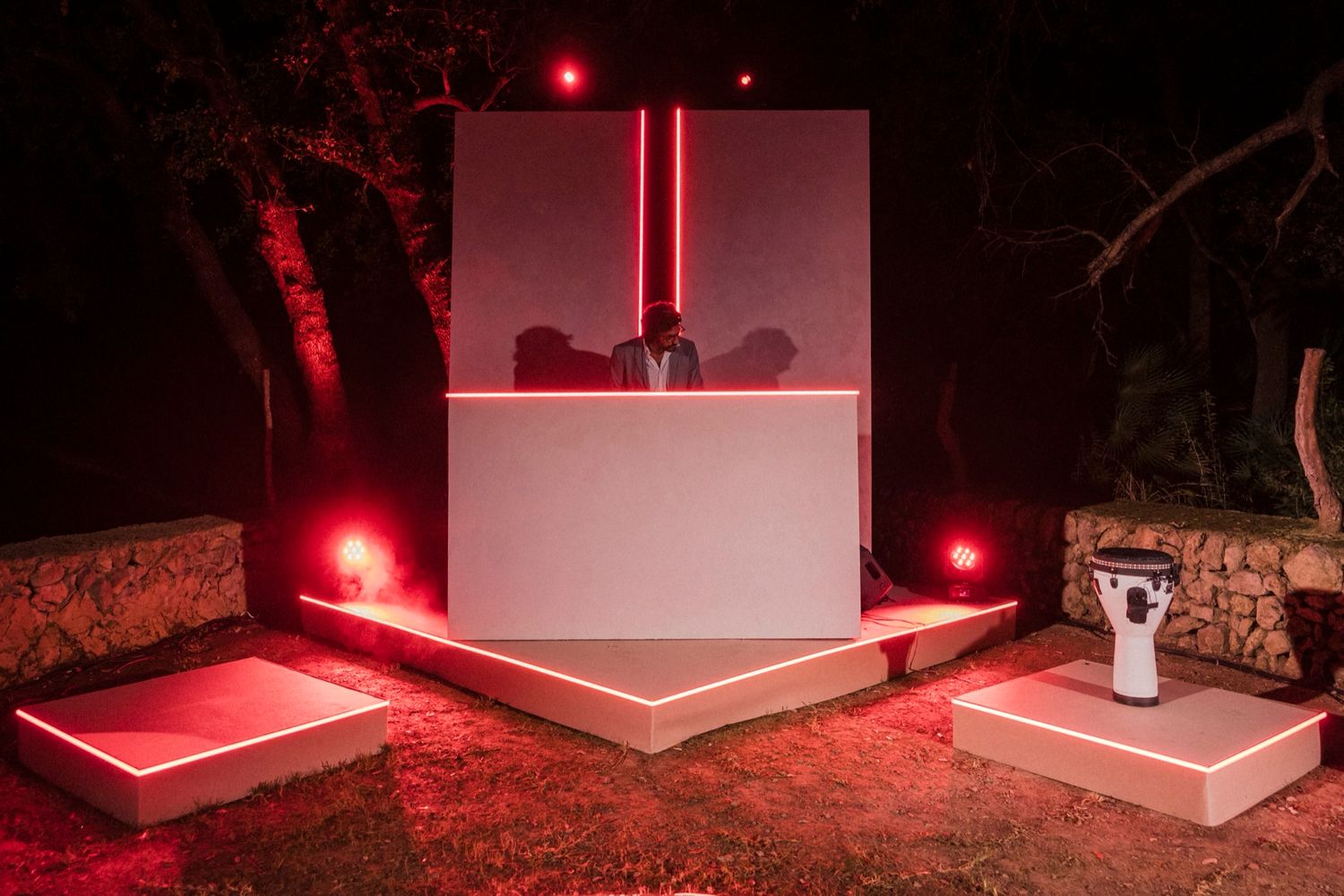 A series of red emergency flares illuminate a dark path at night creating an eerie atmospheric glow.