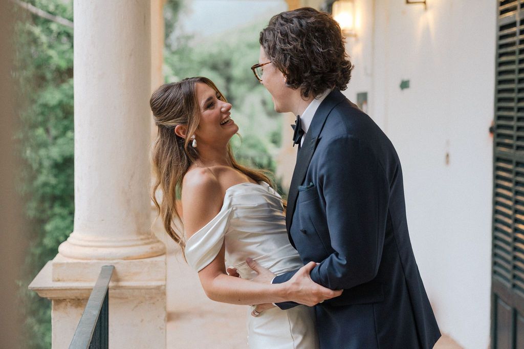 Intimate moment between couple on elegant balcony with colonial architecture.