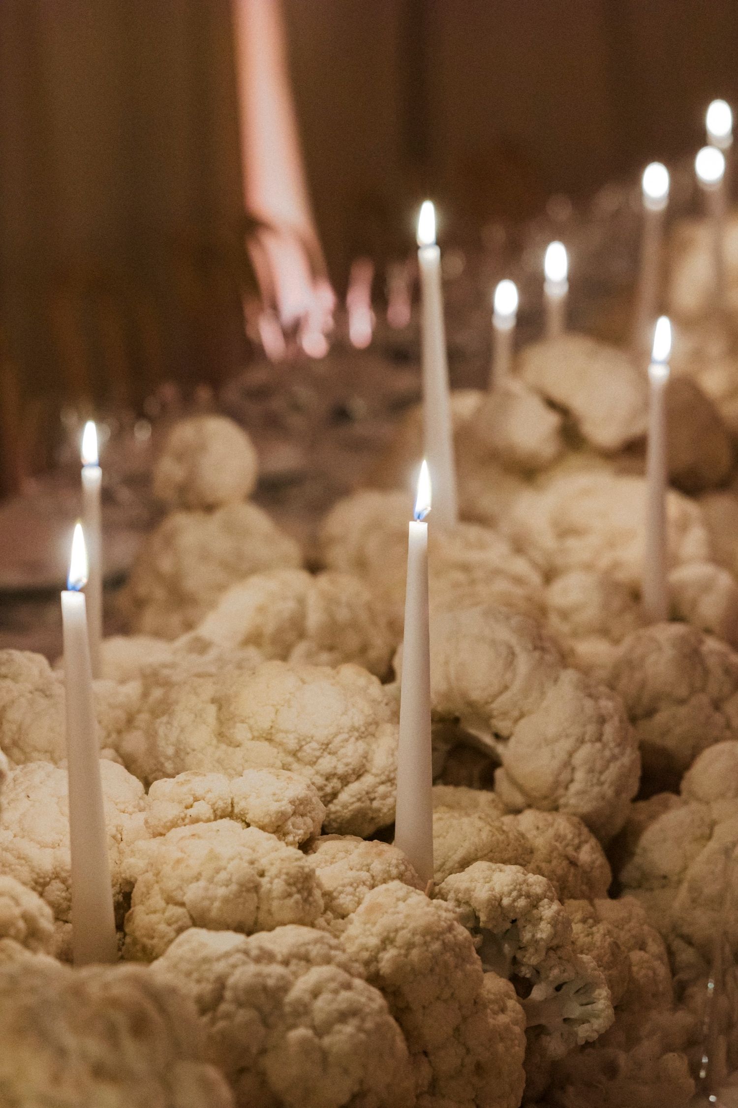 White candles illuminating textured floral arrangements on formal dining table.