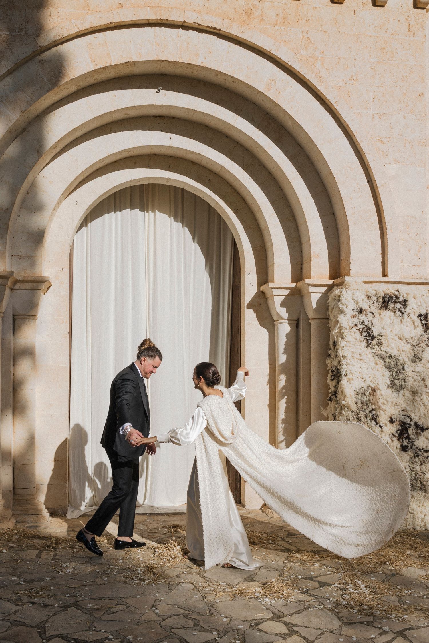 Playful wedding sequence capturing couple's movement through historic stone archway with flowing dress.