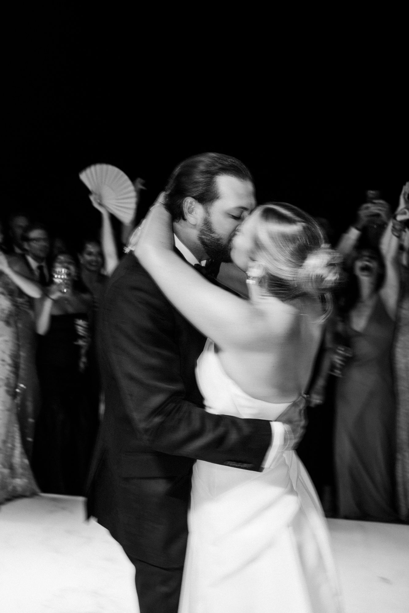 Romantic black and white photo captures newlyweds sharing their first dance at wedding reception.