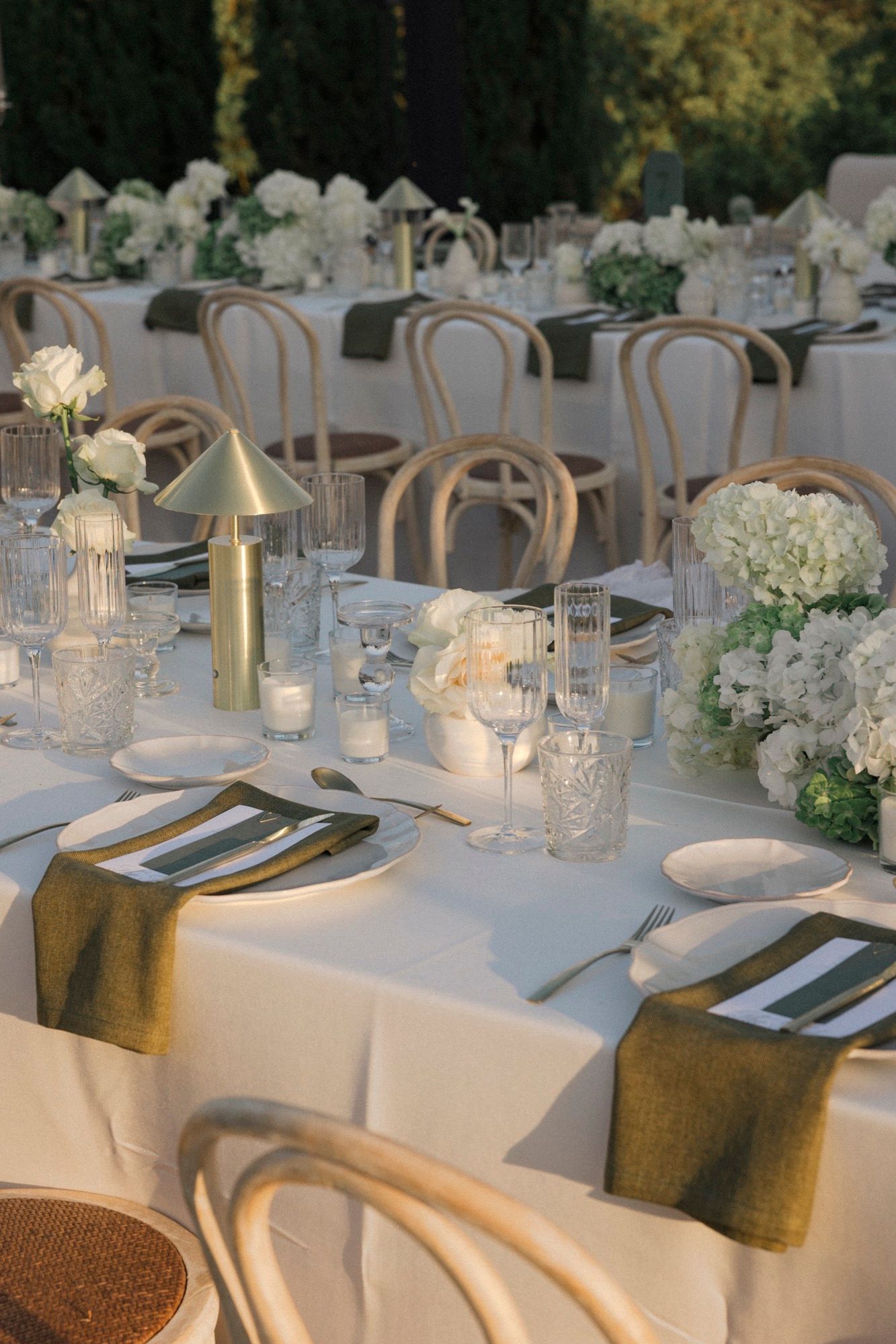 Luxurious wedding table decor with white flowers, gold accents, and crystal candleholders.