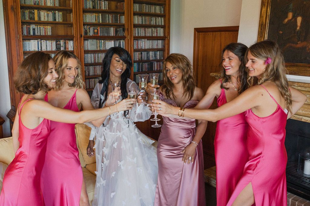 Wedding party poses together in a library wearing pink and white dresses.