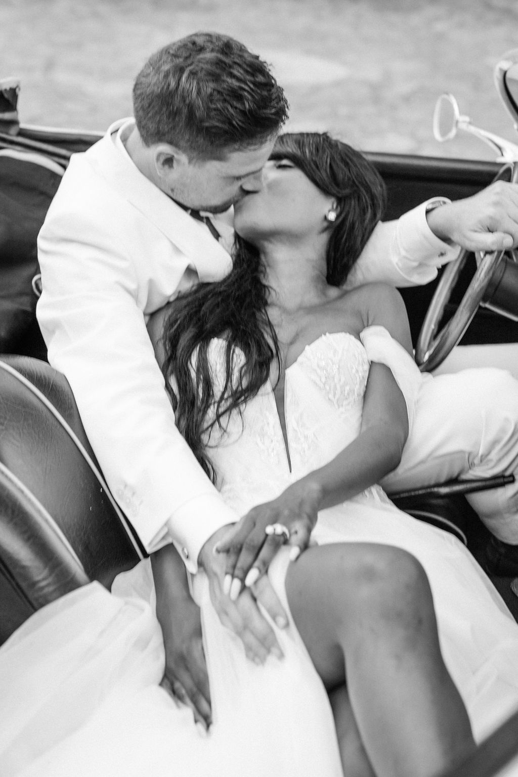 Intimate black and white portrait of newlyweds in classic car.