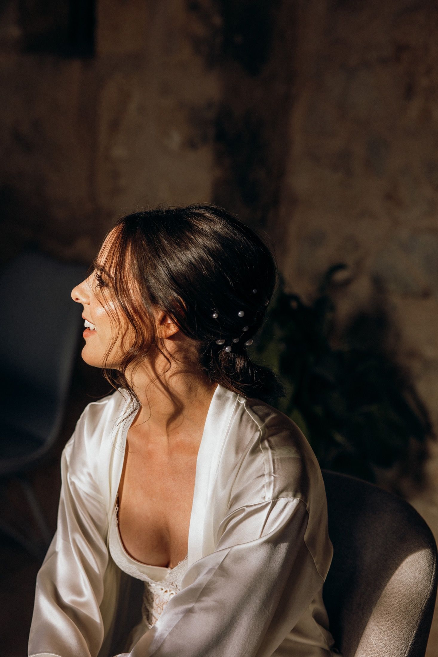 A person in a white silk robe sits in dramatic lighting against a dark background.