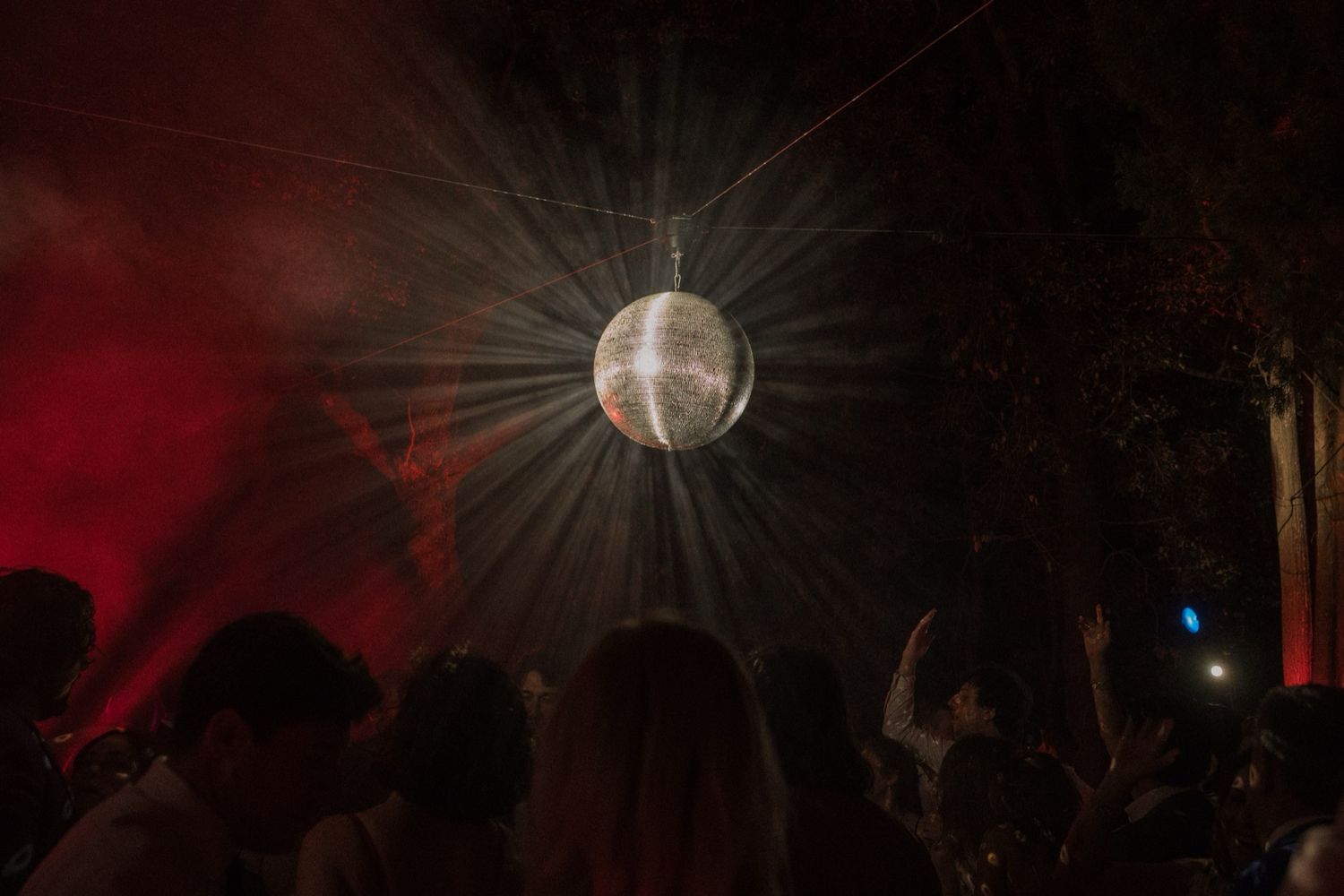 Disco ball reflects light beams across a dark nightclub ceiling creating a sparkling dance floor atmosphere.