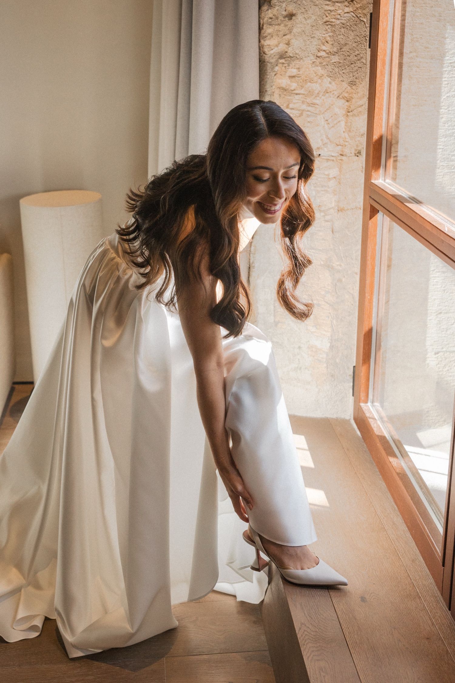 A series of artistic maternity photos showing a woman in white by a window in soft natural light.