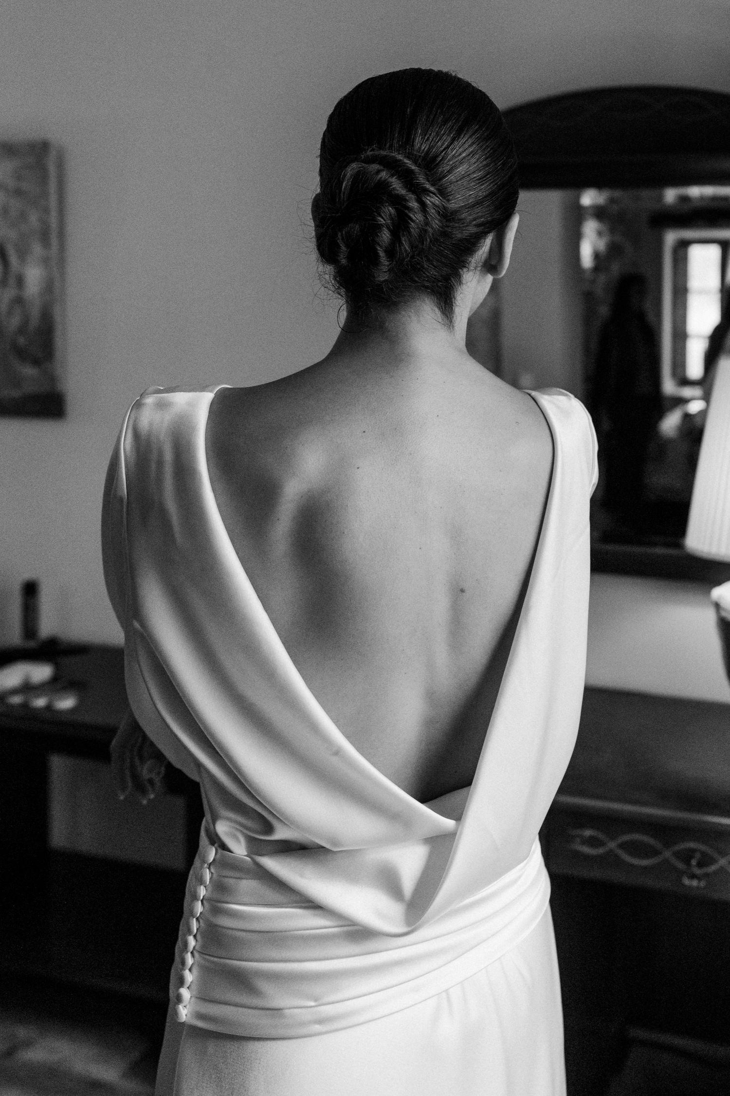 A close-up view of the back details of a white wedding dress with dramatic draping.