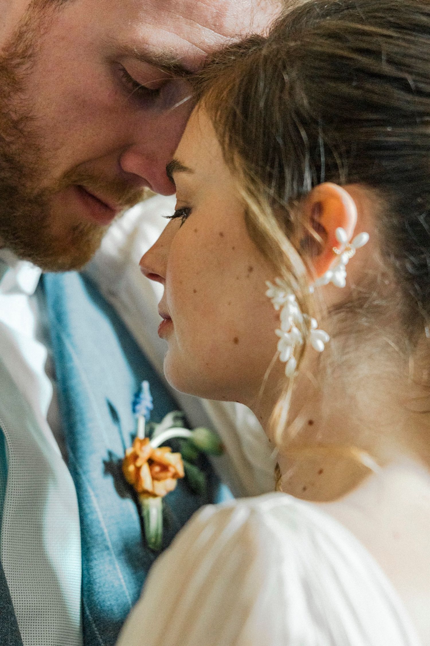 A romantic wedding portrait shows a tender moment between newlyweds in white and turquoise attire.