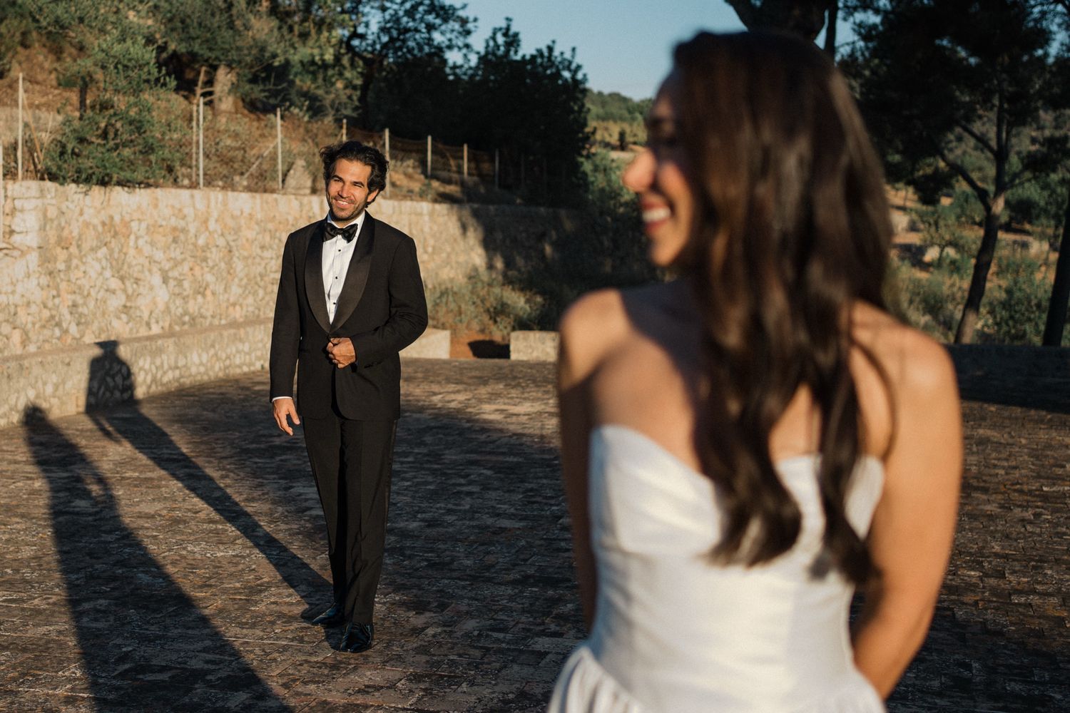 Bride and groom walking together on a rustic stone path during an outdoor wedding photoshoot.