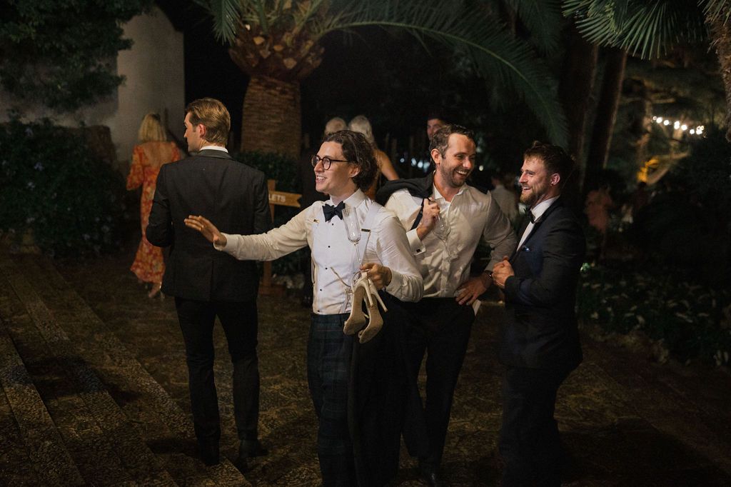 Evening wedding celebration with guests mingling under garden lights.