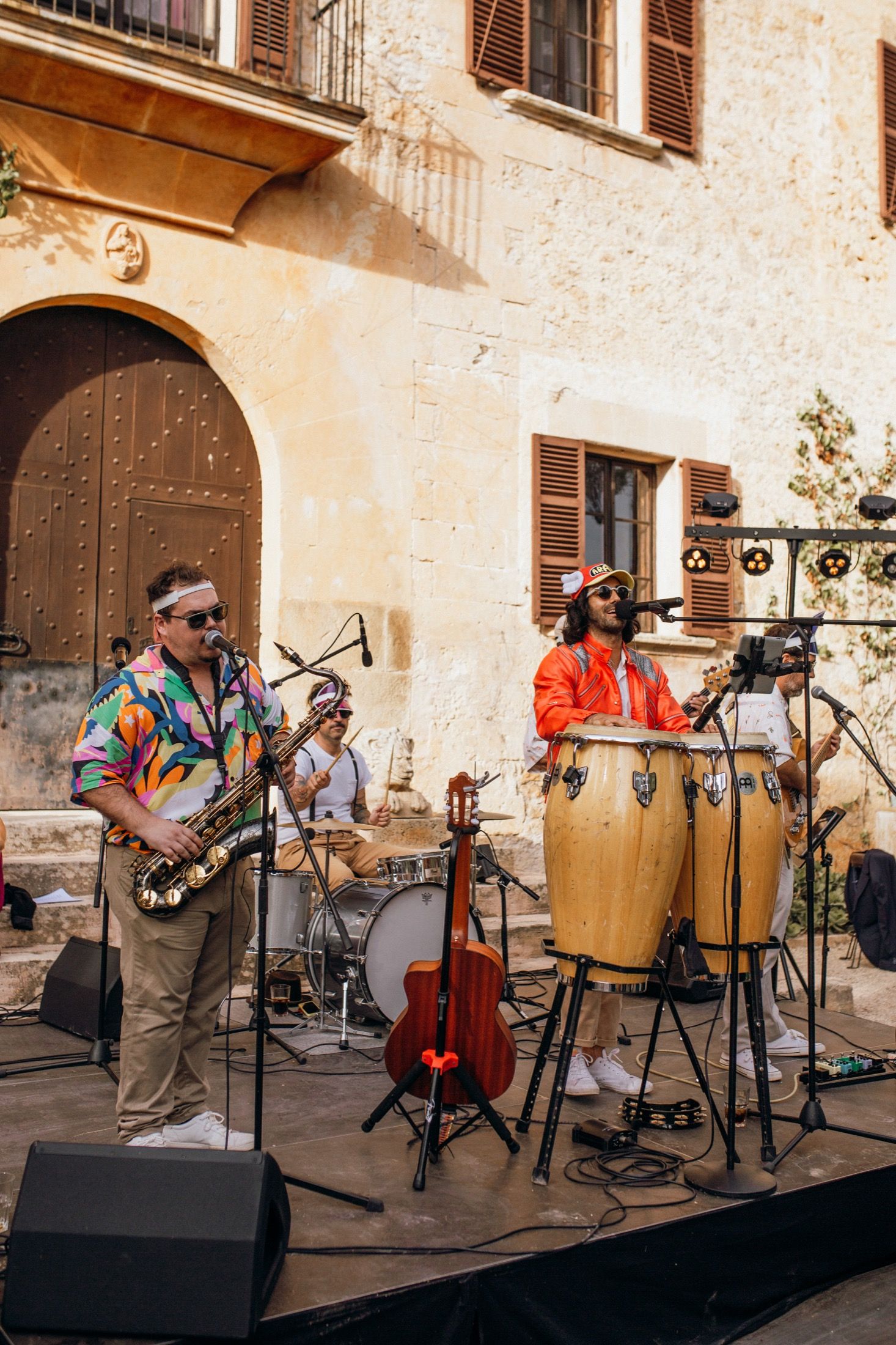 Musicians perform traditional Latin music with percussion instruments and string bass at an outdoor venue.