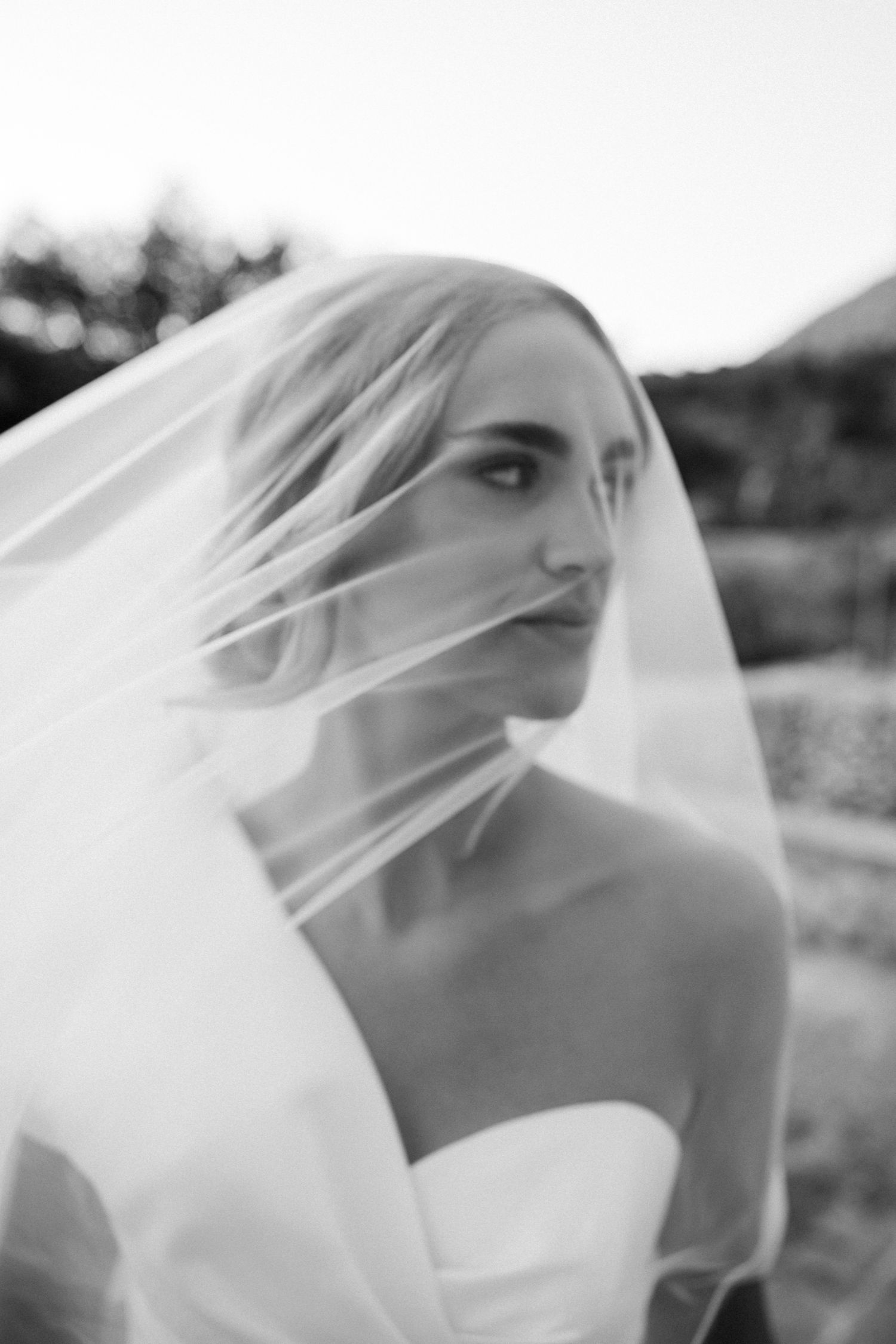 Ethereal black and white portrait series showing a delicate bridal veil flowing in the wind.