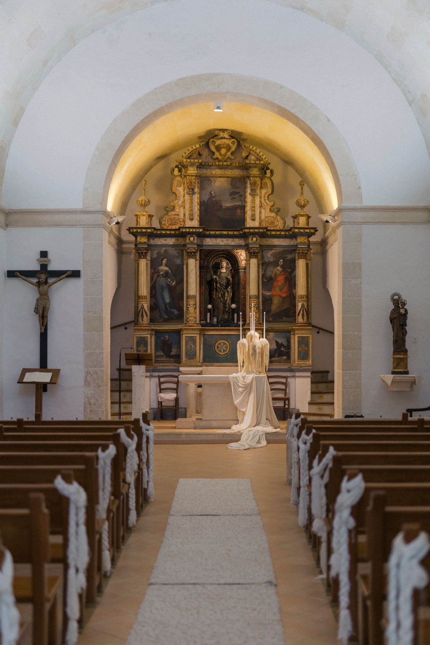 Interior view of an ornate church sanctuary with white aisle runner and arched ceilings.