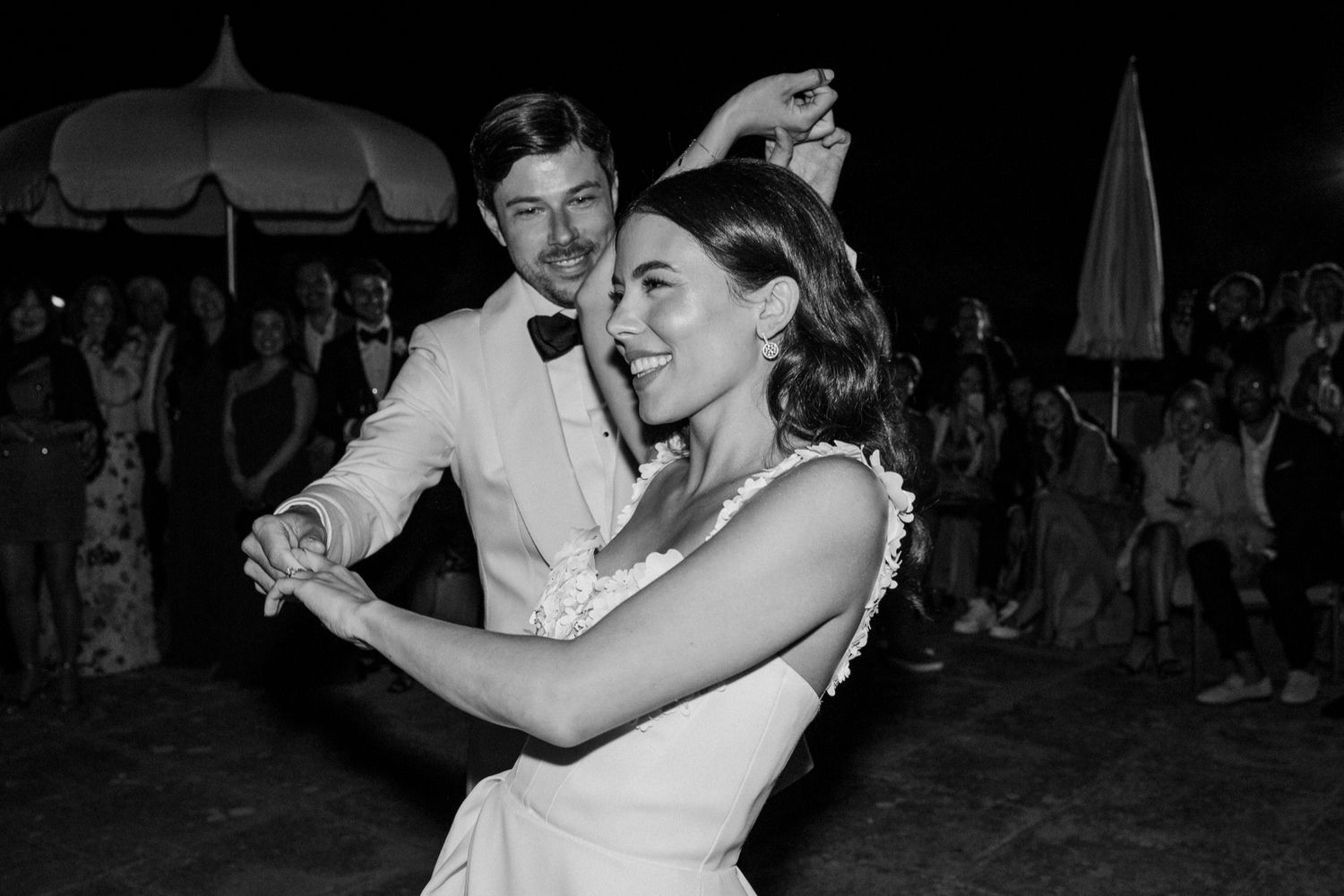 Black and white photo of a bride and groom sharing their first dance at an outdoor wedding reception.