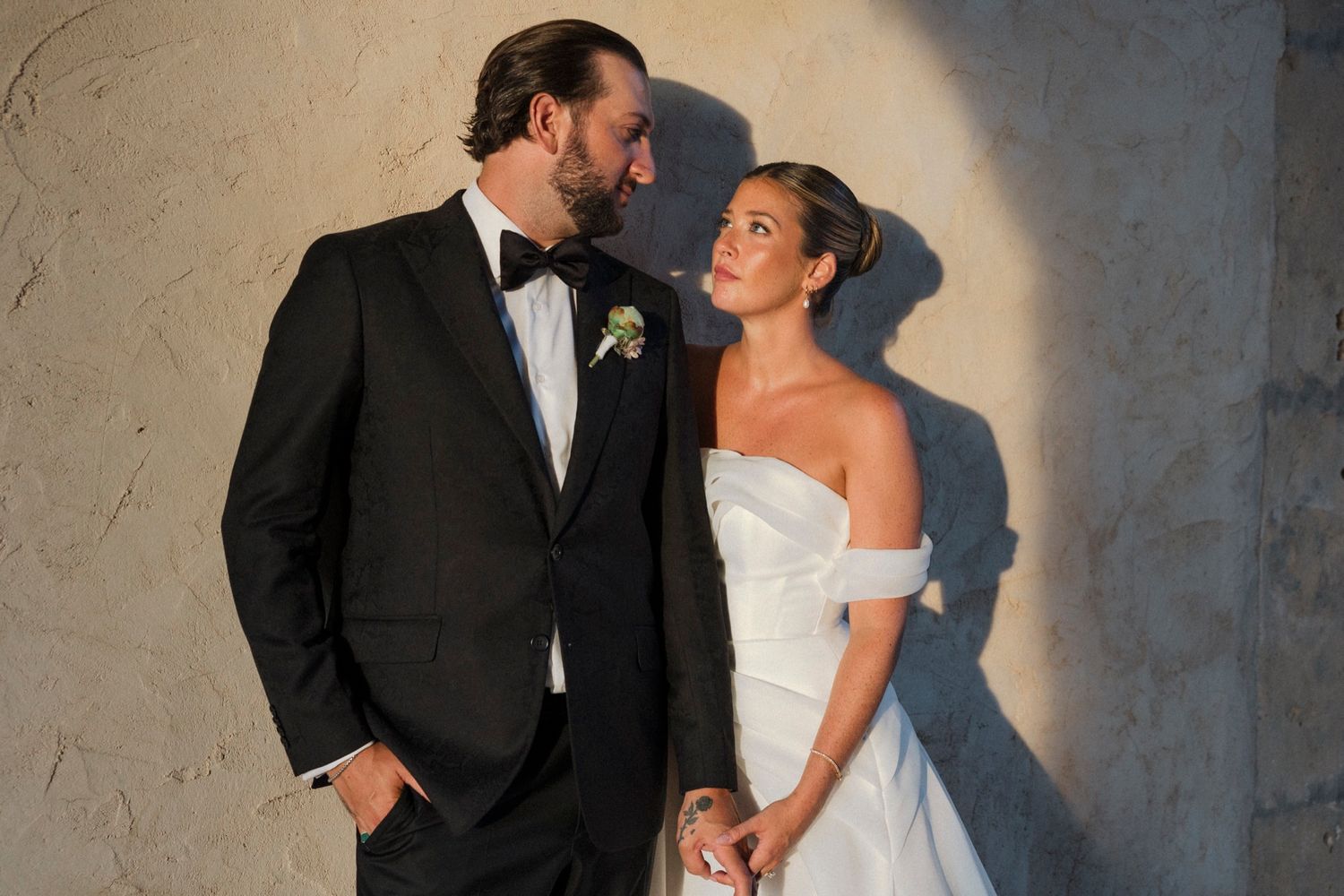A candid wedding portrait capturing a tender moment between newlyweds in golden light.