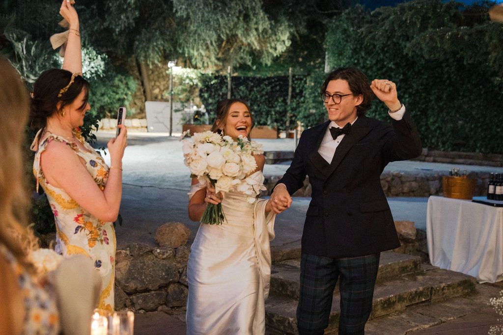 Wedding couple and guests celebrating on an outdoor garden patio at dusk.