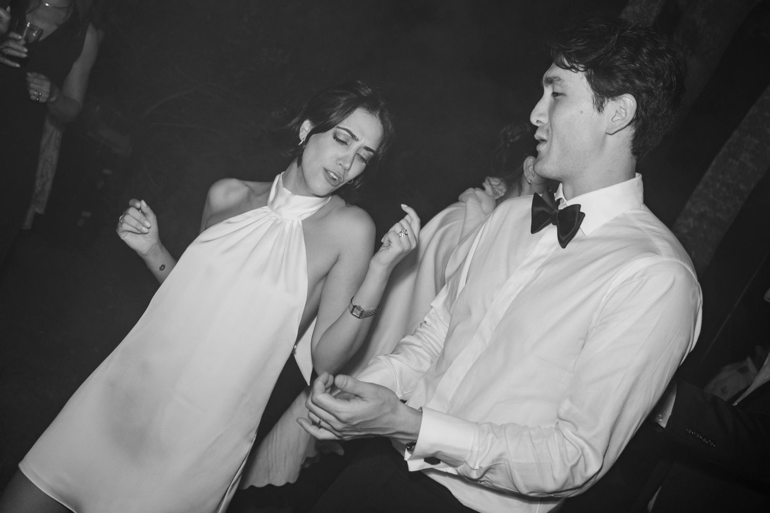 A sequence of black and white photos showing two people engaged in a playful interaction at a social gathering.