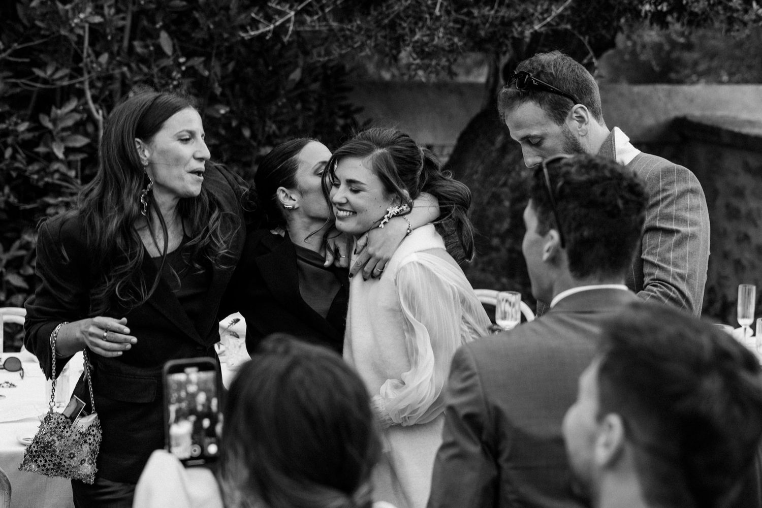 Wedding guests raise their phones to capture a special moment during an outdoor celebration.