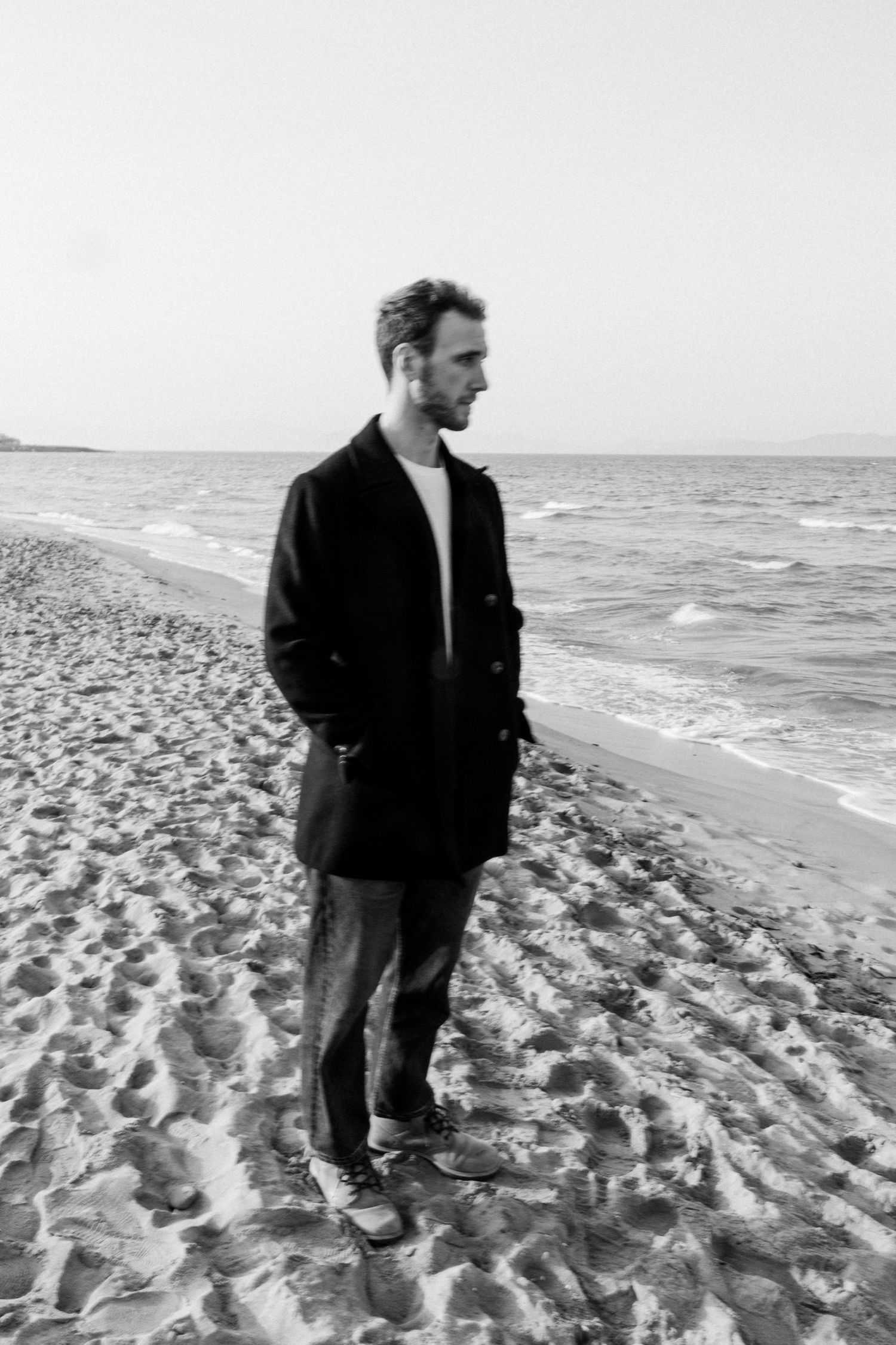 Black and white photo sequence of someone walking along a beach shoreline with waves and sand visible.