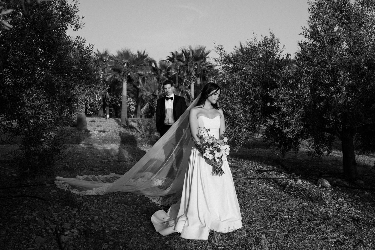 A series of black and white wedding photos showing romantic moments in an outdoor garden setting.