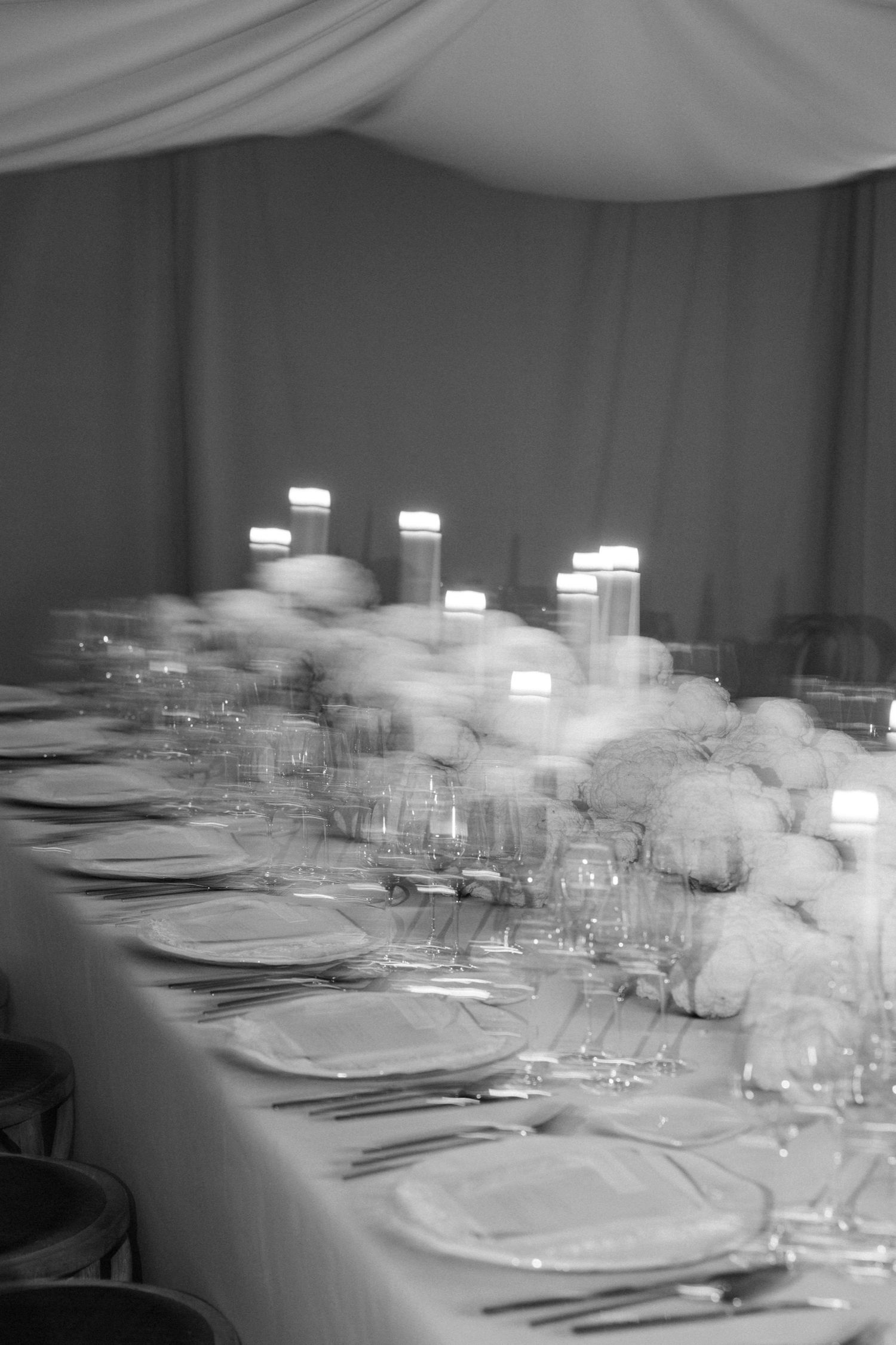 Black and white image of an elegant table setting with glowing candles and place settings.