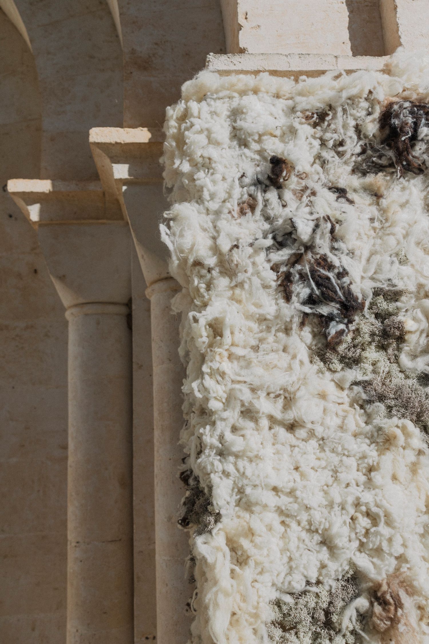 Textured white installation against stone columns creating an artistic display.