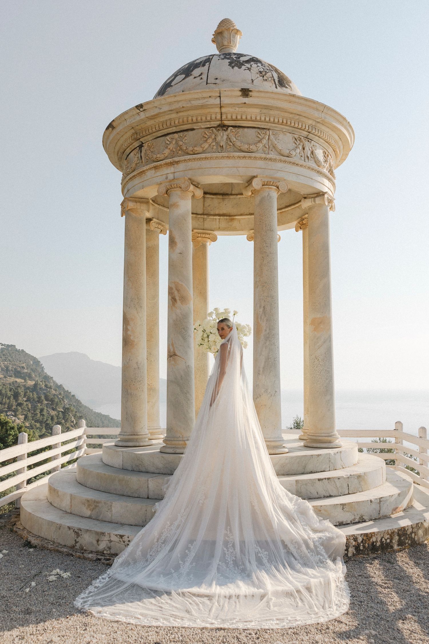 Bridal portrait session in a Mediterranean-style stone gazebo showcasing a flowing cathedral length veil.