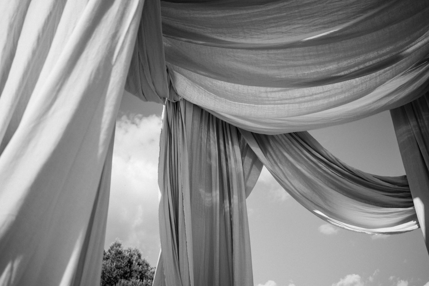 Elegant white fabric drapes create a romantic ceiling canopy with soft folds and gentle curves in an event space.