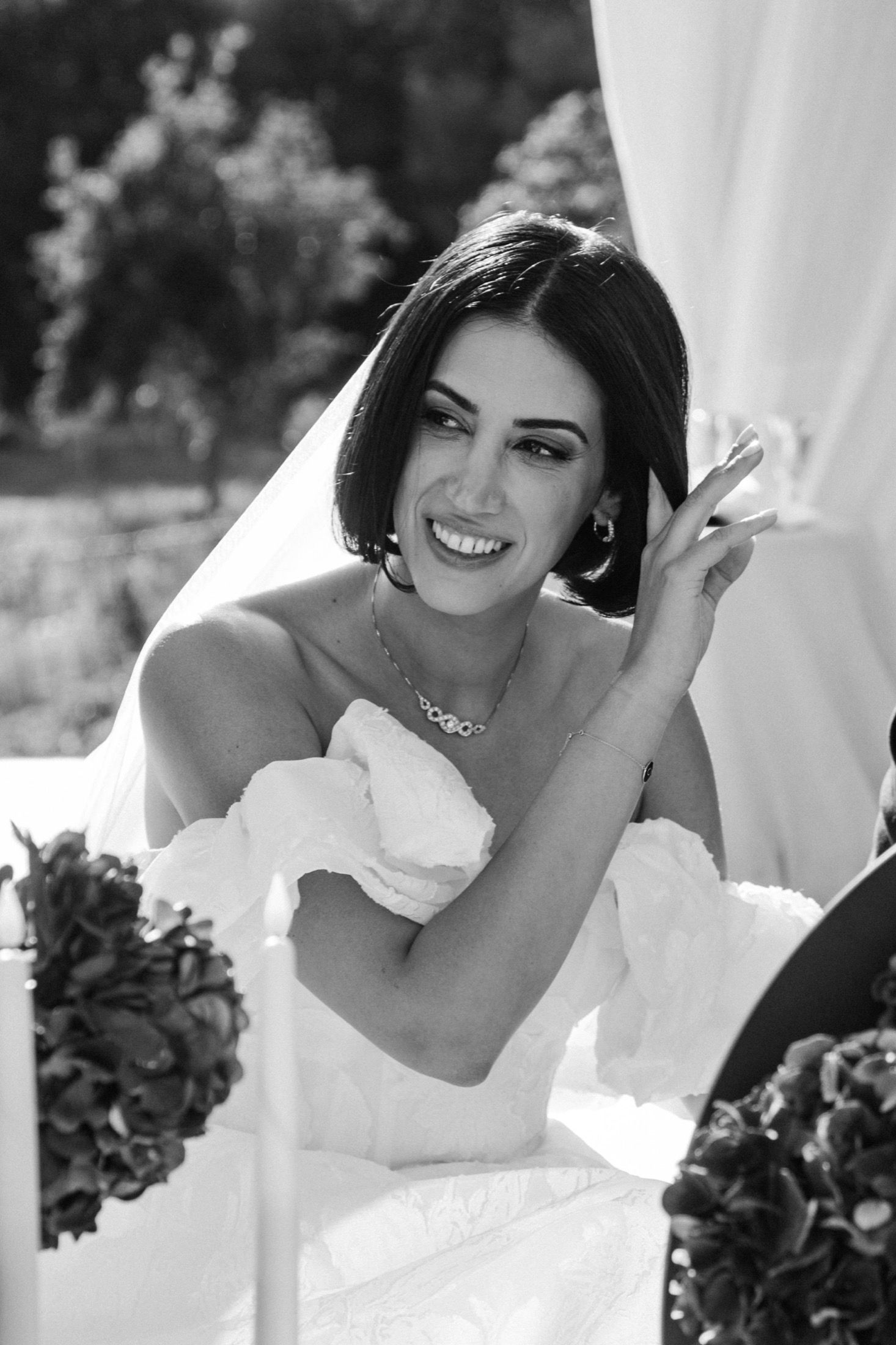 Black and white photo series of a bride in a strapless wedding gown posing with her bouquet against white fabric.