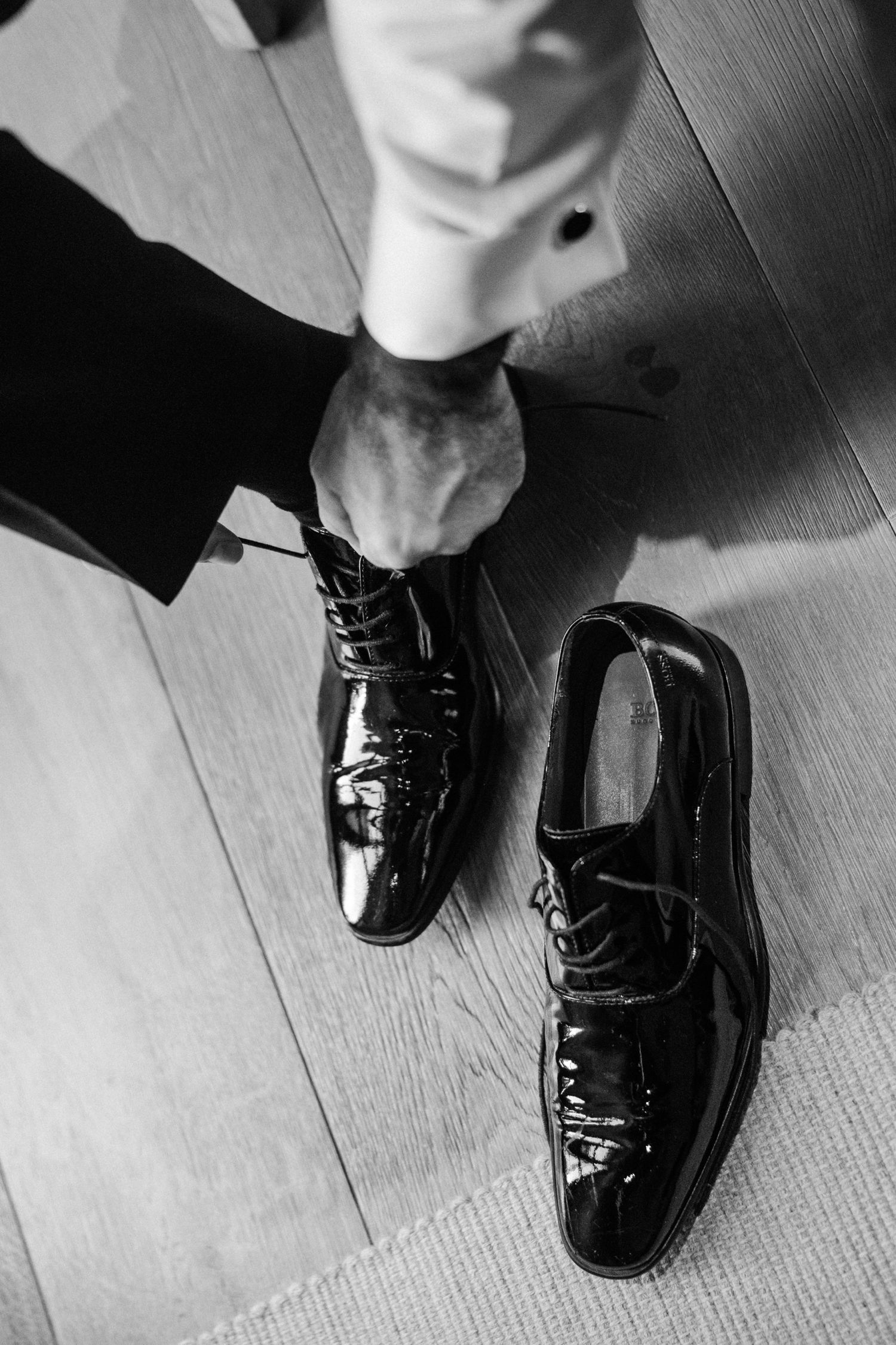 Black patent leather dress shoes shown in sequence against a wooden floor.