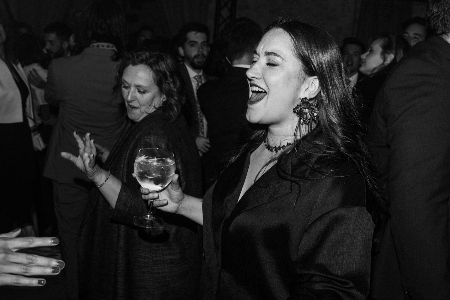 A group of people dancing and laughing together at a formal event in black and white.