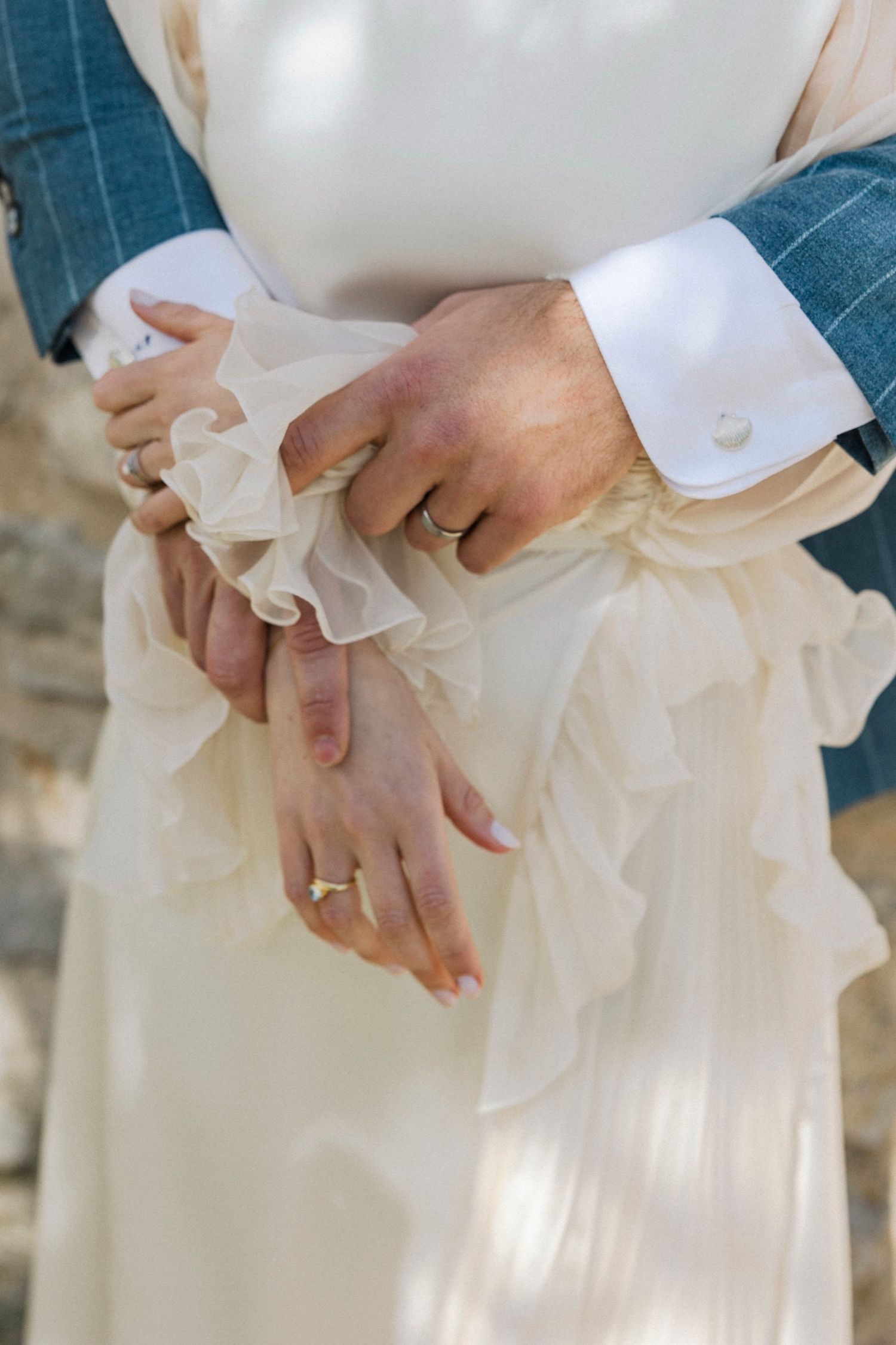 Close-up view of hands adjusting delicate white ruffles on a wedding dress.