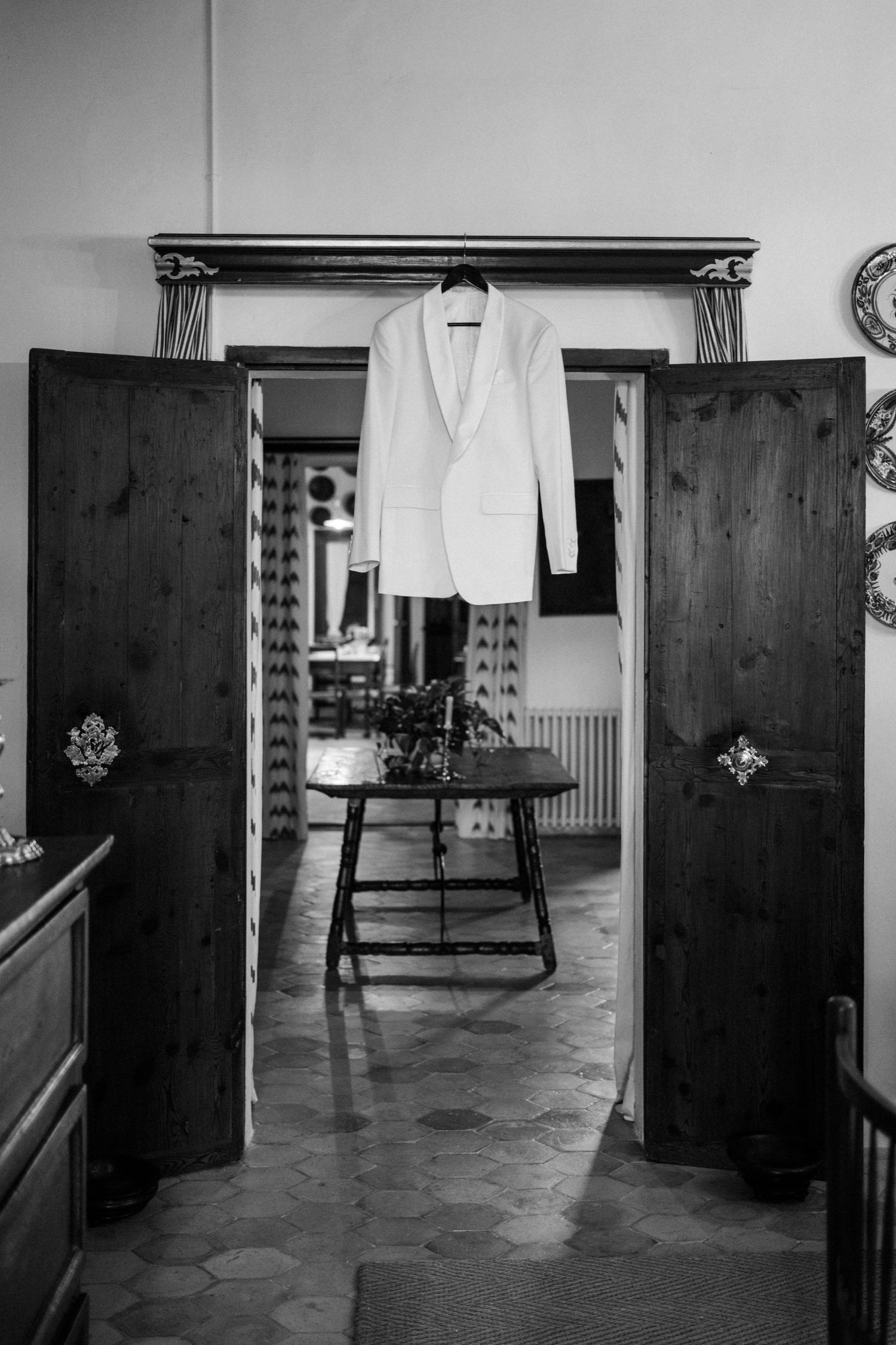 Black and white photos show a dark wooden wardrobe in a minimalist interior space with tiled floors and white walls.